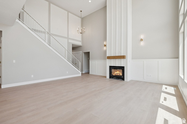 1471 Colbey Loop Santa Clara, UT 84765 - Photo 10 of 45 Two-story living area featuring a prominent fireplace with a wood mantel, light wood-finish flooring, and a contemporary chandelier