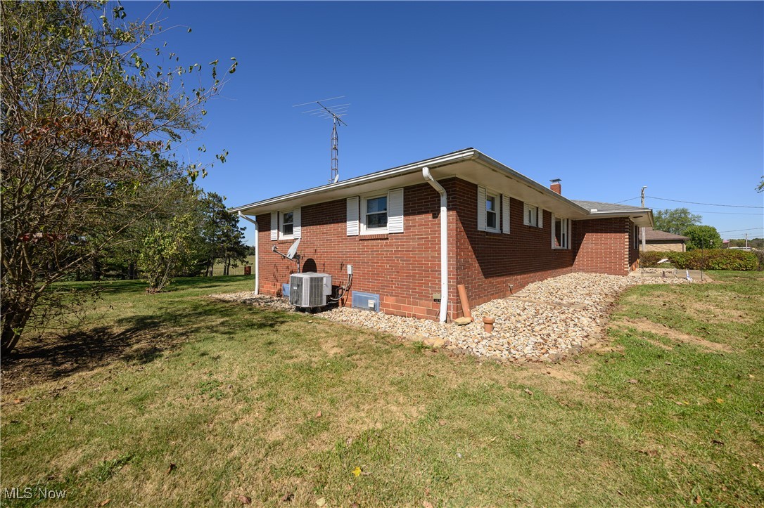 View of home's exterior featuring brick siding, a lawn, and a chimney