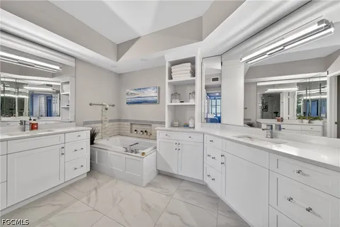 a large white bathroom with a sink a large mirror and a bathtub