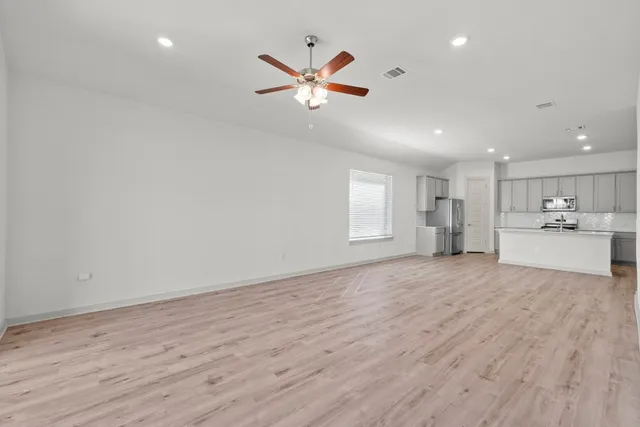 a view of an empty room with a window and wooden floor