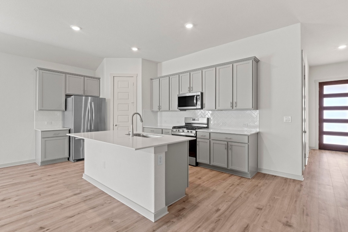 2201 Bobtail Pass Leander, TX 78641 - Photo 5 of 30 a kitchen with white cabinets and stainless steel appliances