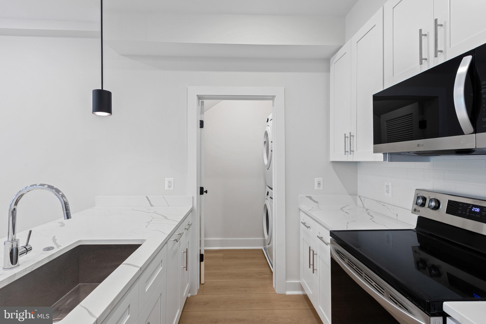 2236 40th Street Northwest, Unit FIVE Washington, DC 20007 - Photo 8 of 37 a kitchen with stainless steel appliances granite countertop a sink and a stove top oven with wooden floor