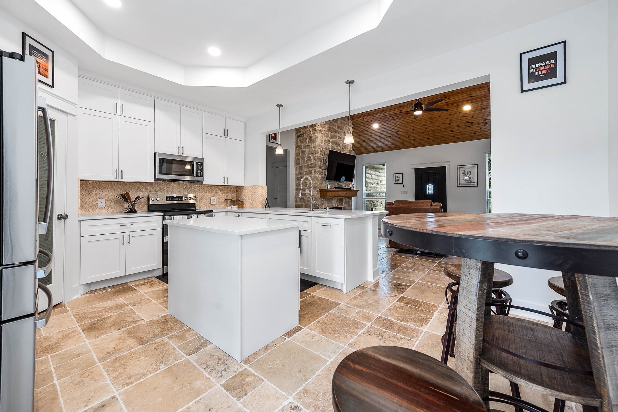 8032 Short Road Needville, TX 77461 - Photo 12 of 50 The kitchen seamlessly connects to the main living area, featuring sleek white cabinetry, stainless steel appliances, and a spacious island that enhances both functionality and flow. The open design and warm wood accents create a comfortable and inviting atmosphere throughout the home.