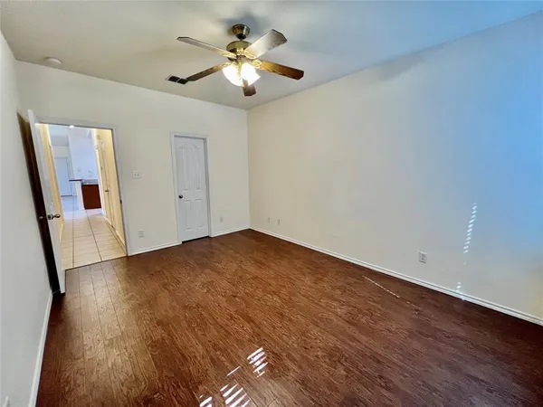 an empty room with wooden floor and ceiling fan