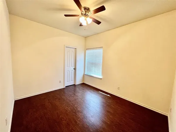 a view of an empty room with window and a ceiling fan