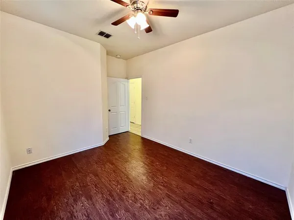 an empty room with wooden floor fan and windows