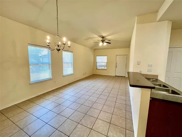 a view of an empty room with window and chandelier fan