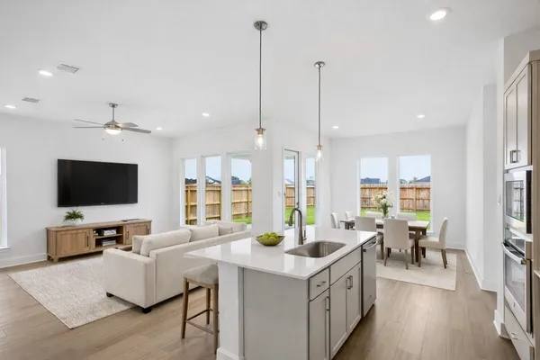 a large kitchen with kitchen island granite countertop a sink a counter top space appliances and living room view