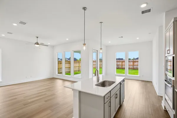 a kitchen with stainless steel appliances granite countertop a sink a stove a refrigerator a center island and wooden floor
