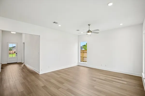 a view of an empty room with wooden floor and a window
