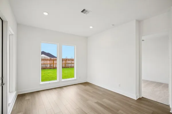 an empty room with wooden floor and windows