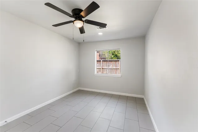 an empty room with ceiling fan and window