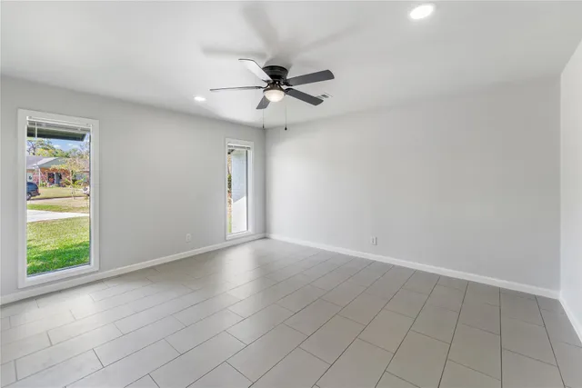 an empty room with windows and fan