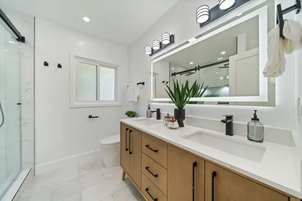 a bathroom with a double vanity sink mirror and next to a window