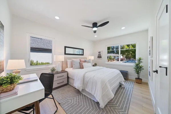 a bedroom with a large bed a potted plant and a window