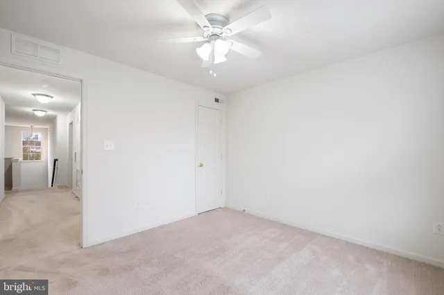 an empty room with a chandelier fan and windows
