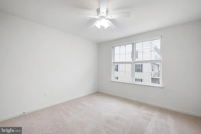 an empty room with chandelier fan and windows