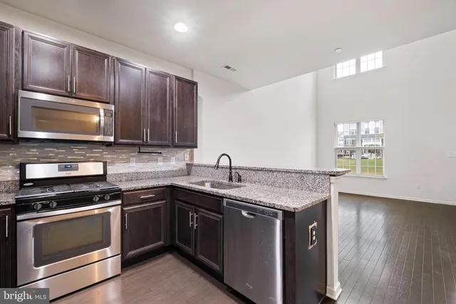 a kitchen with stainless steel appliances granite countertop wooden cabinets stove top oven and sink