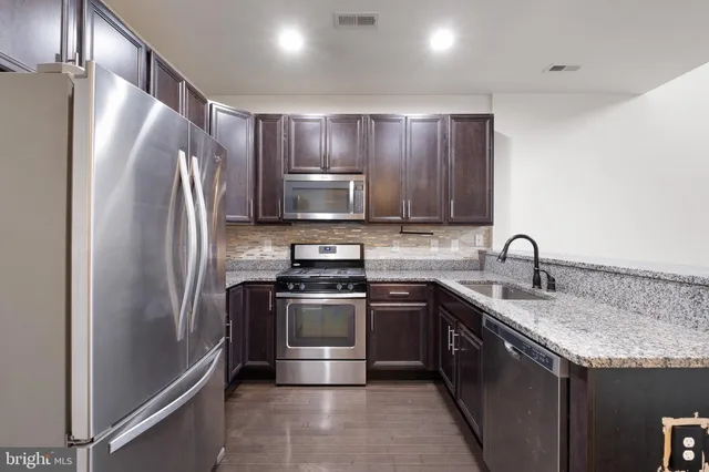 a kitchen with stainless steel appliances granite countertop a sink stove and refrigerator