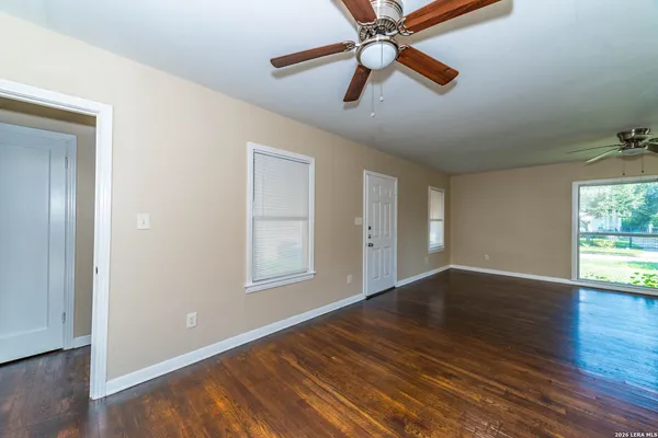an empty room with wooden floor fan and windows
