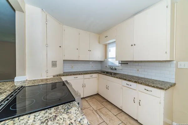 a kitchen with granite countertop white cabinets and white appliances