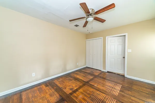 a view of a big room with wooden floor and a ceiling fan