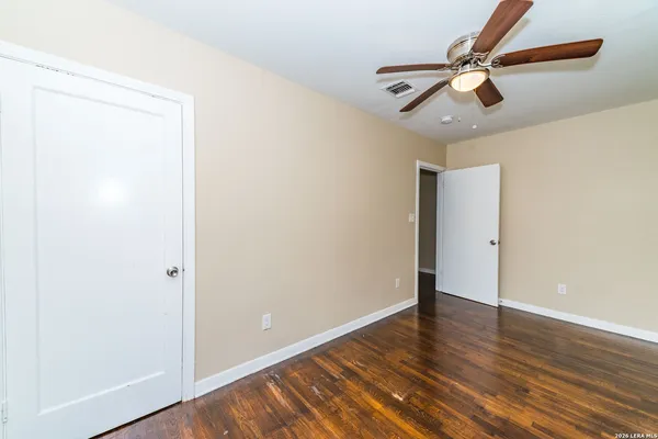 an empty room with wooden floor ceiling fan