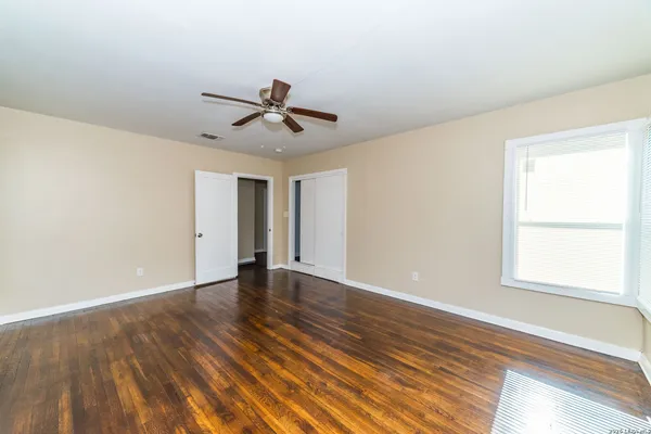a view of empty room with wooden floor and fan