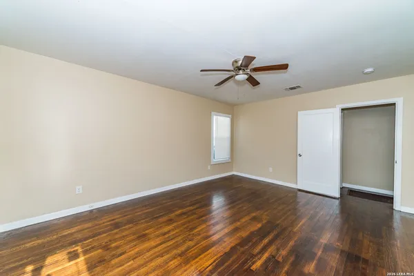 a view of a big room with wooden floor and a chandelier fan