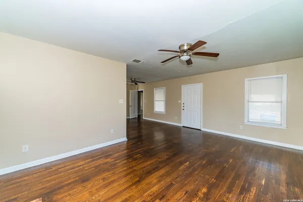 an empty room with wooden floor and windows
