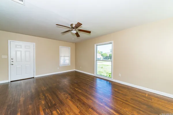 an empty room with wooden floor and windows
