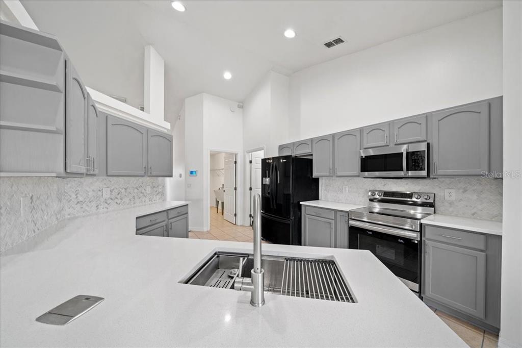 5659 Southwest 89th Place Ocala, FL 34476 - Photo 21 of 76 a kitchen with stainless steel appliances a stove a sink a microwave a refrigerator and cabinets