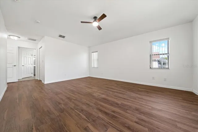 an empty room with wooden floor and windows