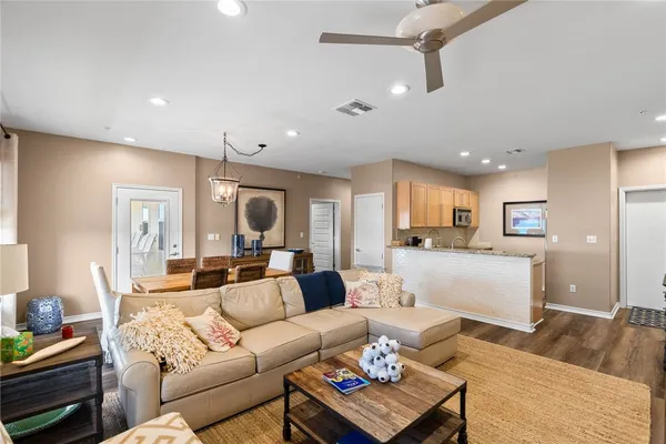 a living room with furniture kitchen view and a wooden floor