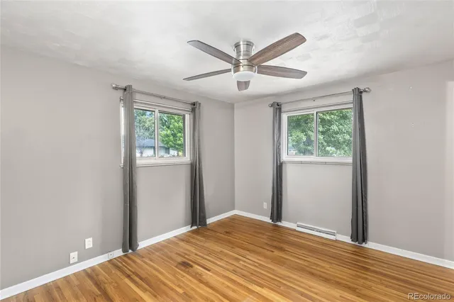 a view of a bedroom with wooden floor and a ceiling fan