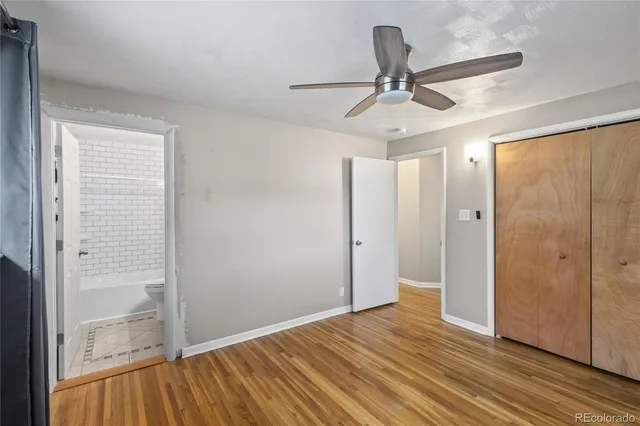 a view of empty room with wooden floor and ceiling fan