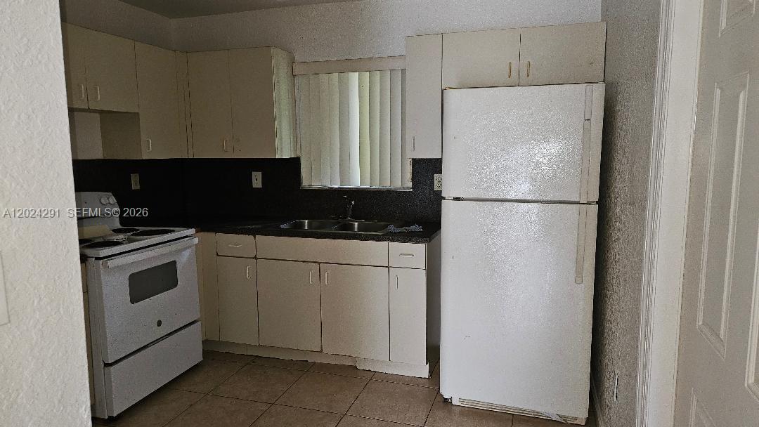 11970 Southwest 217th Street Miami, FL 33170 - Photo 4 of 10 a white refrigerator freezer sitting in a kitchen