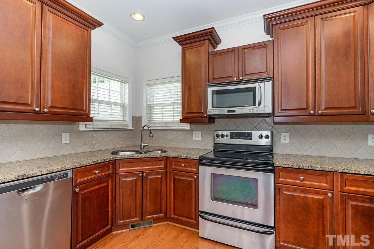 1217 Harp Street Raleigh, NC 27604 - Photo 9 of 27 a kitchen with granite countertop wood cabinets stainless steel appliances and a window