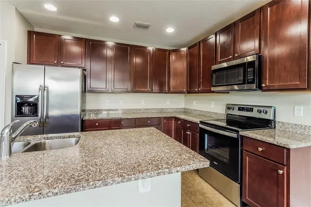 a kitchen with granite countertop wooden cabinets a sink and stainless steel appliances
