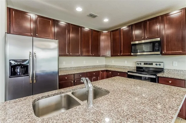a kitchen with kitchen island granite countertop a sink stainless steel appliances and cabinets