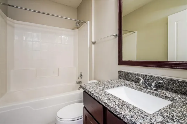 a bathroom with a granite countertop sink mirror toilet and bathtub