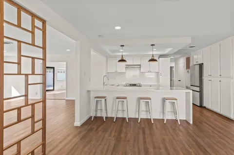 a large white kitchen with white cabinets and wooden floor