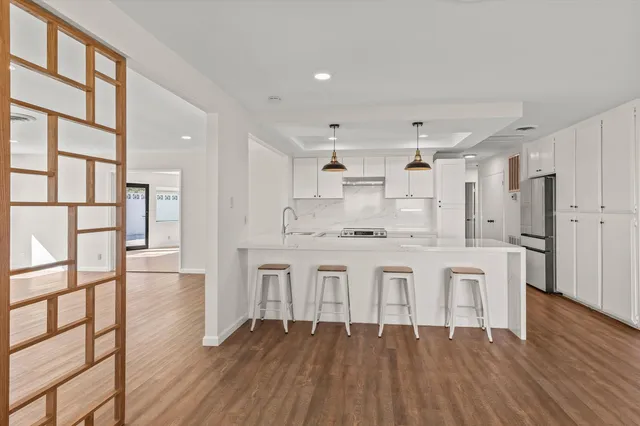 a large white kitchen with white cabinets and wooden floor