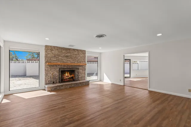 a view of an empty room with wooden floor fireplace and a window