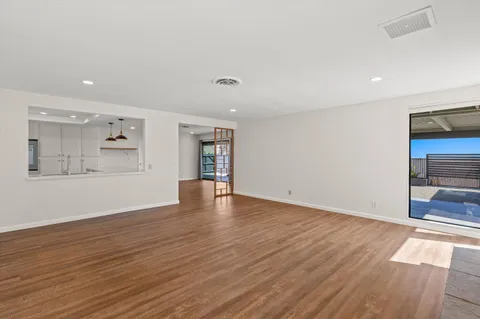 a view of an empty room with wooden floor and a window