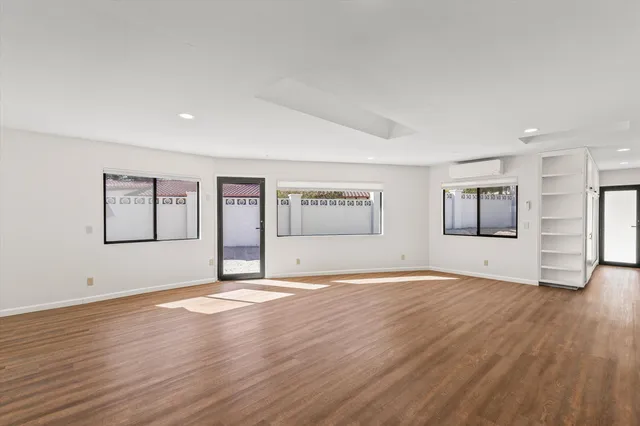 a view of an empty room with window and wooden floor