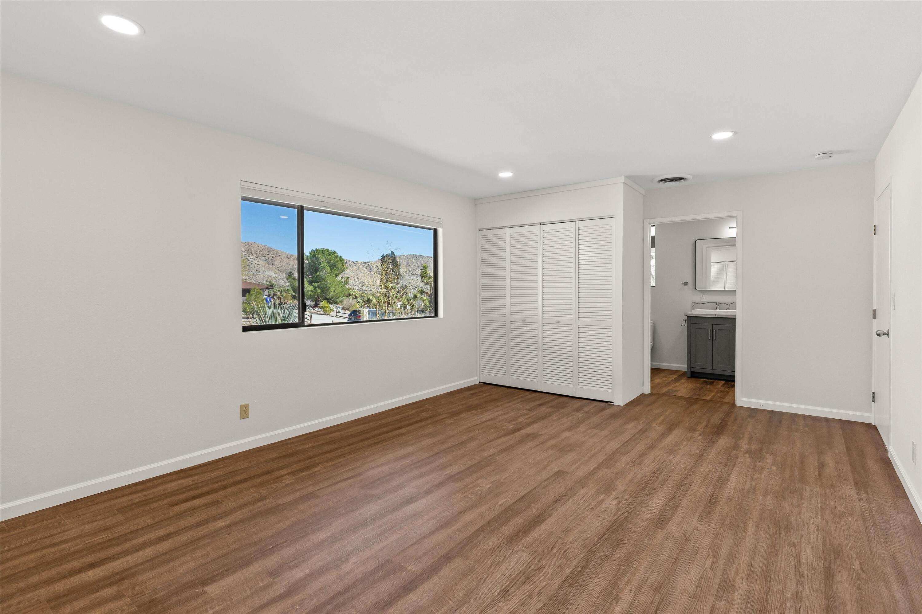 7458 Cardillo Trail Yucca Valley, CA 92284 - Photo 21 of 47 a view of an empty room with wooden floor and a window