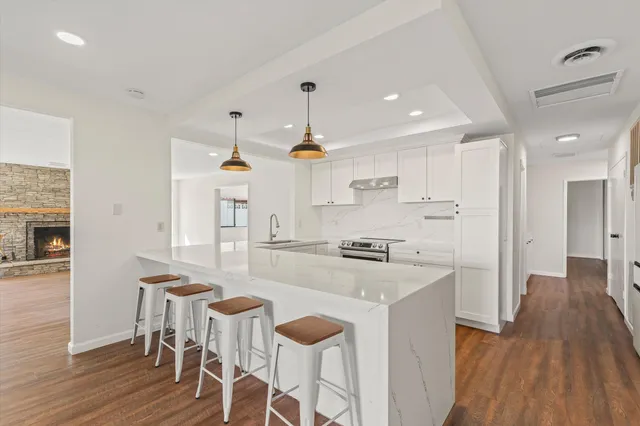 a kitchen with stainless steel appliances granite countertop a stove top oven a refrigerator a sink and a dining table with wooden floor