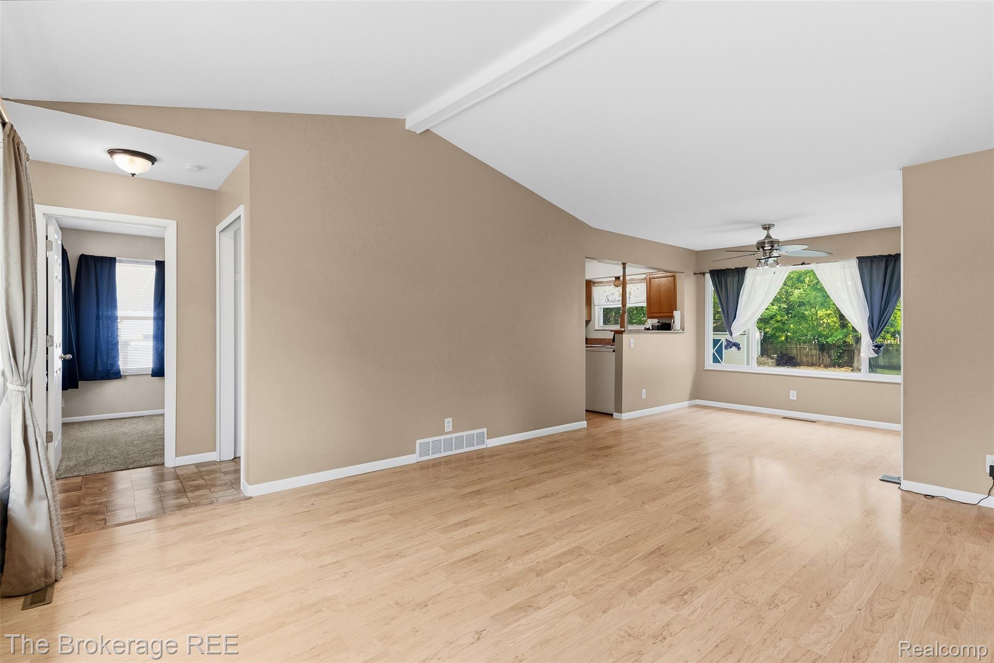 6509 Silver Lake Road Linden, MI 48451 - Photo 13 of 43 Spacious living area featuring light wood-finish flooring, vaulted ceilings, and a pass-through to the kitchen