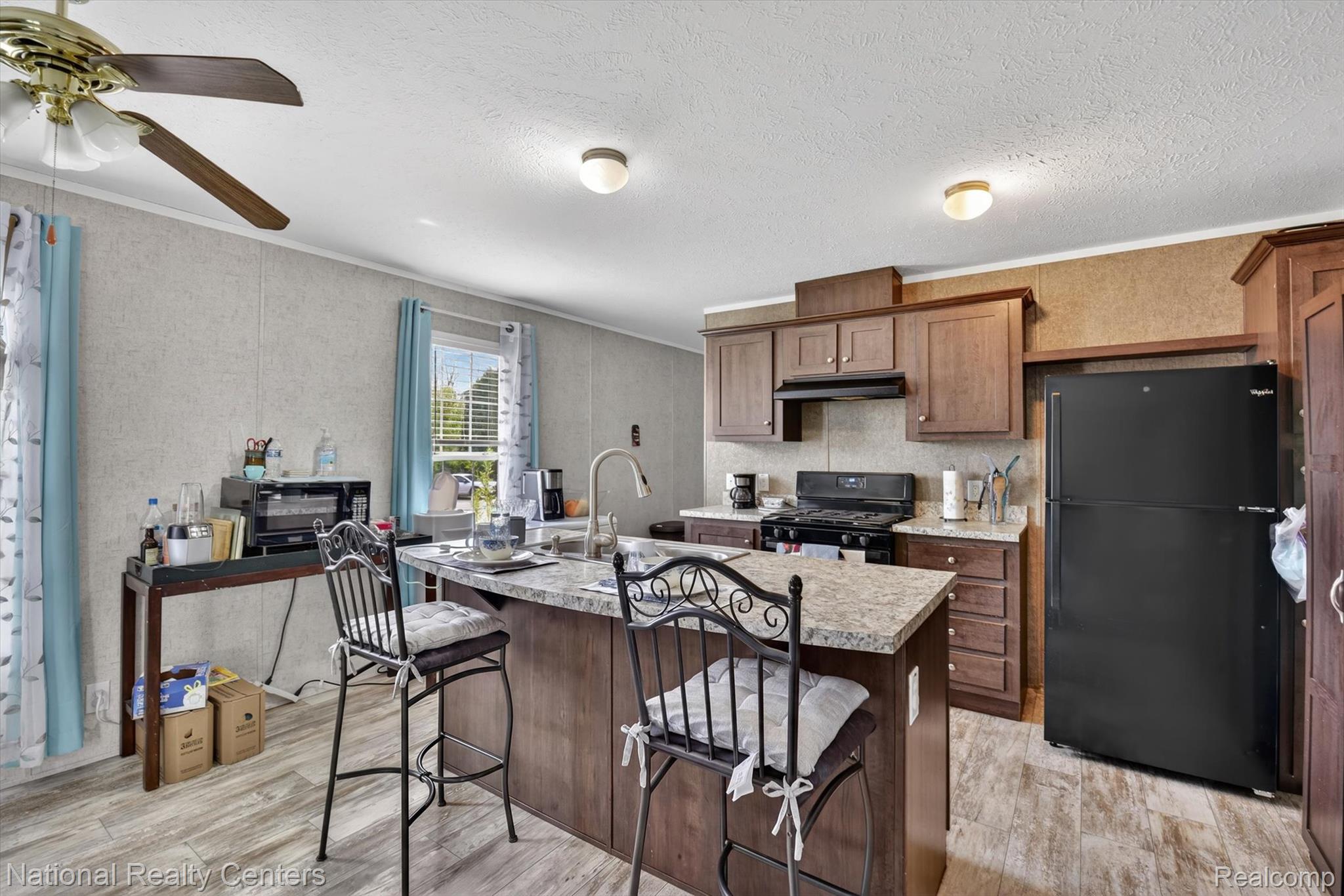 2735 South Wagner Road, Unit 103 Ann Arbor, MI 48103 - Photo 4 of 20 Kitchen featuring black appliances, a breakfast bar, ornamental molding, light wood-style flooring, and an island with sink